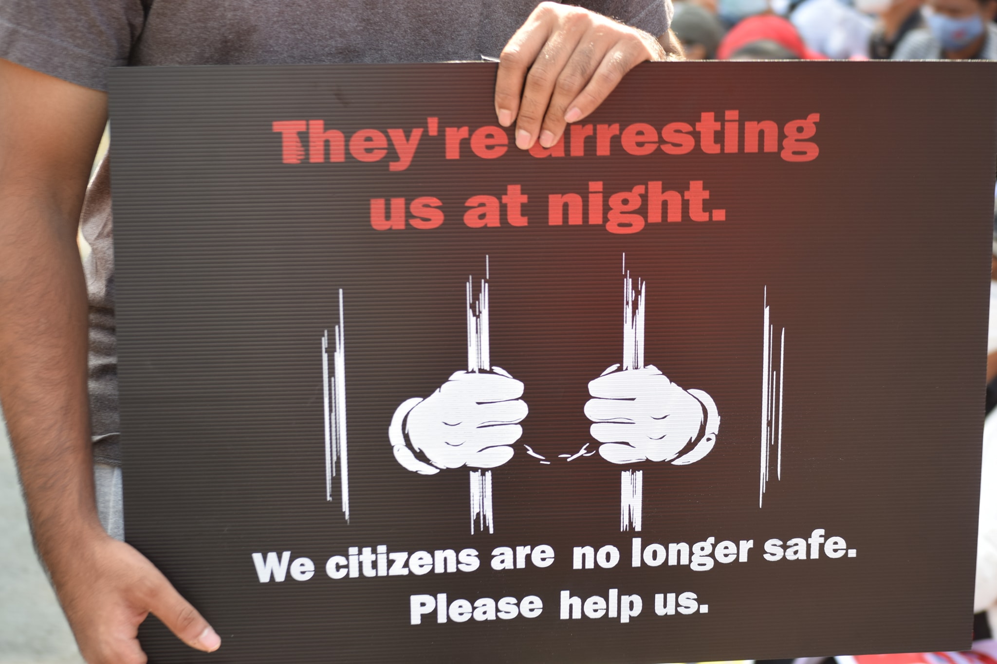 Protest sign reading They're arresting us at night